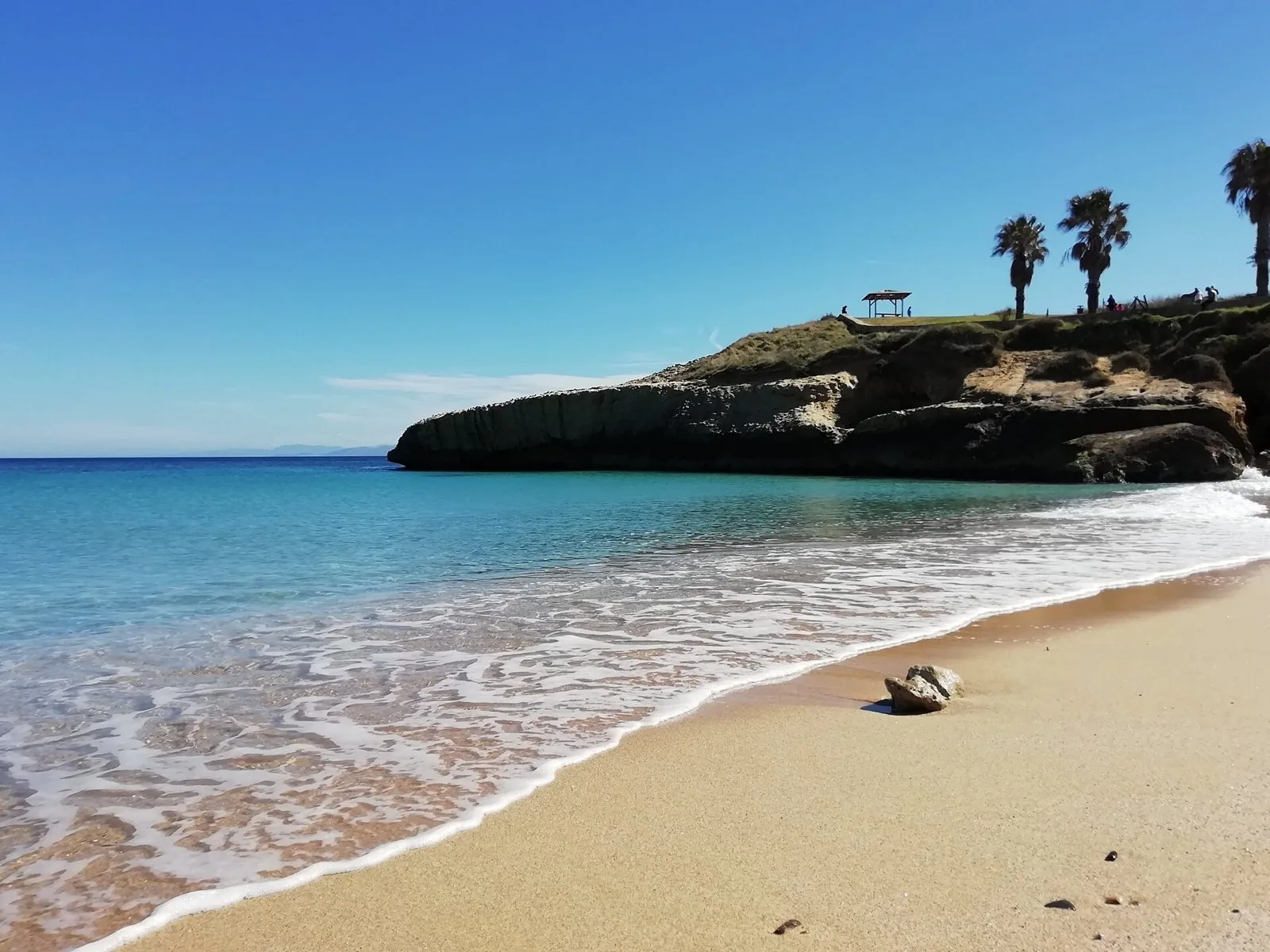 La spiaggia di Balai a Porto Torres quasi deserta: sabbia dorata, acqua trasparente e una scogliera calcarea con palme